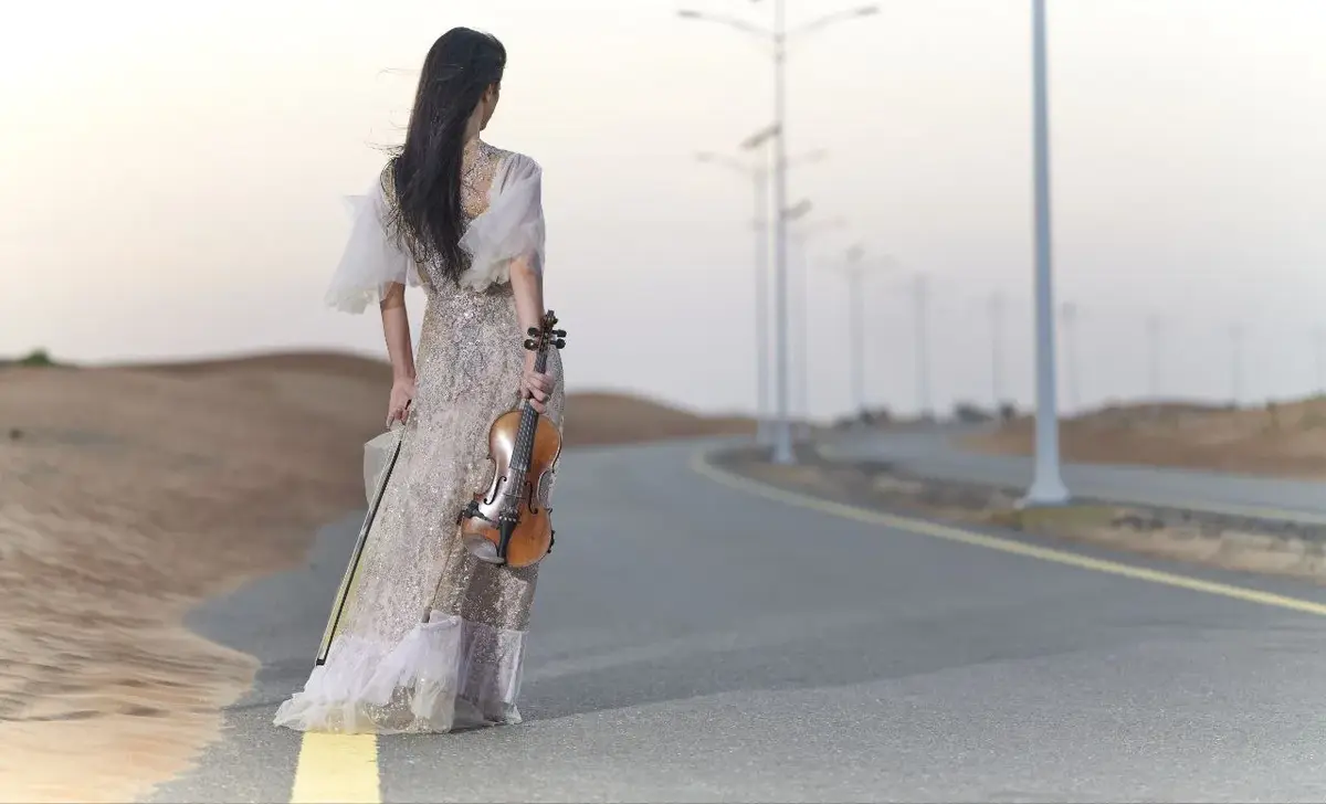 Anna Petrasian walking on desert road with violin